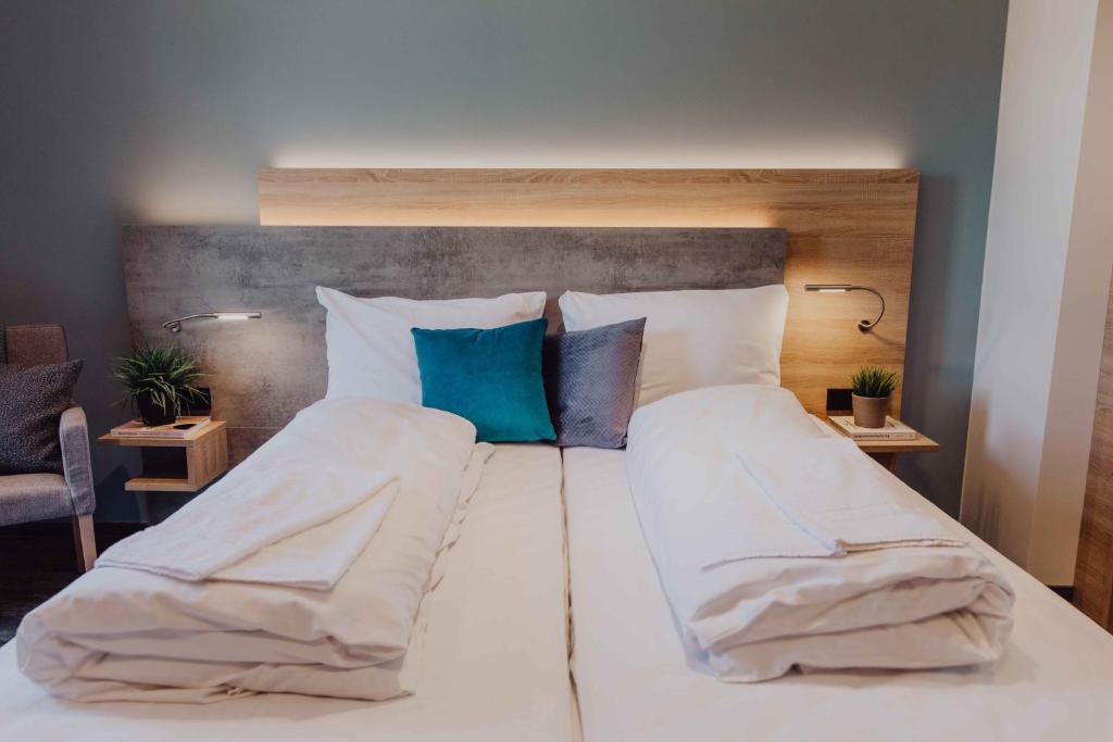uma cama grande com lençóis brancos e almofadas azuis em Pascals Ruhestube em Mörsdorf