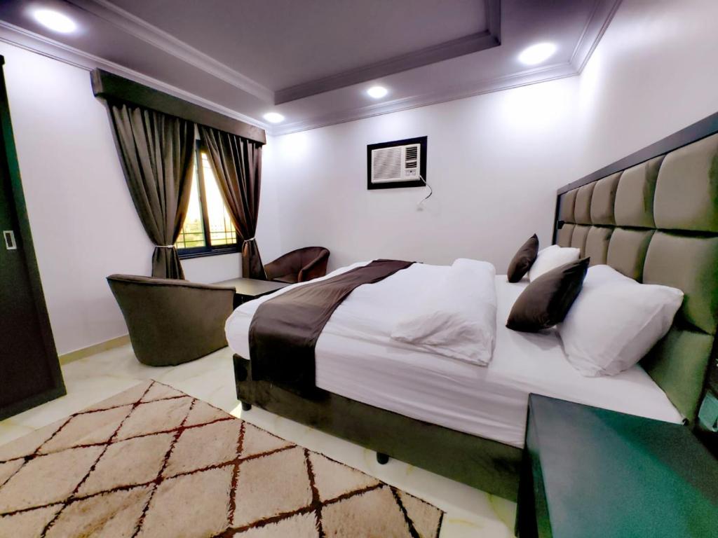 a bedroom with a bed and a chair and a window at Batw باتوا لشقق المخدومة in Al Baha