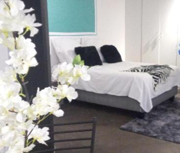 een slaapkamer met een bed met witte lakens en zwarte kussens bij Chic Urban Maboneng Getaway, Free Wi-Fi in Johannesburg
