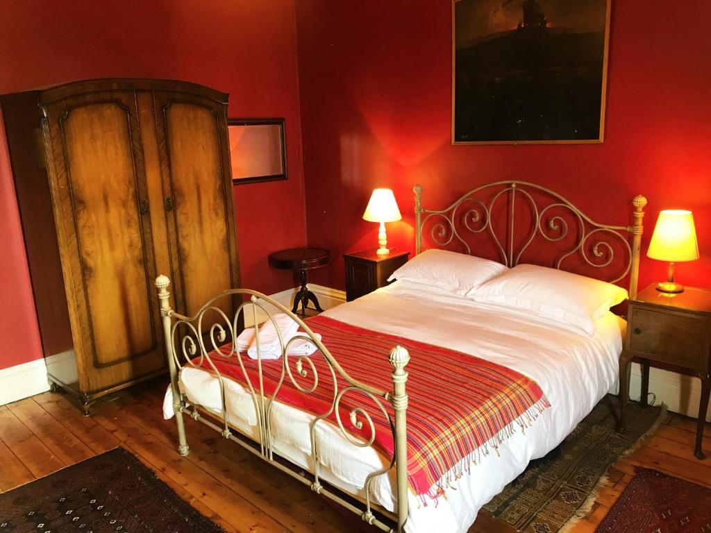 a bedroom with a bed with a red wall at Grand top floor apartment in the Royal Bank House in Maybole