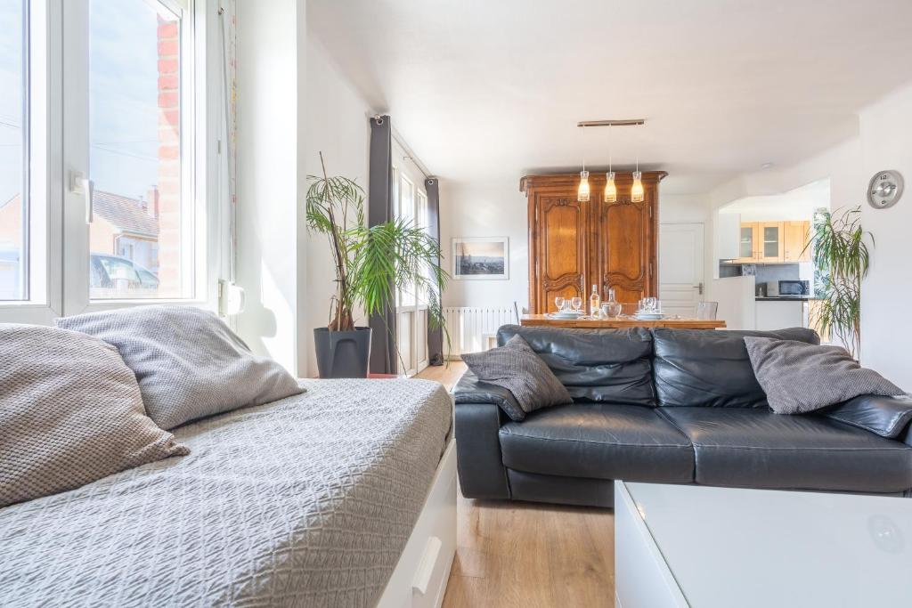 een woonkamer met een zwarte leren bank en een keuken bij Maison confortable, terrasse et jardin à Amiens in Amiens