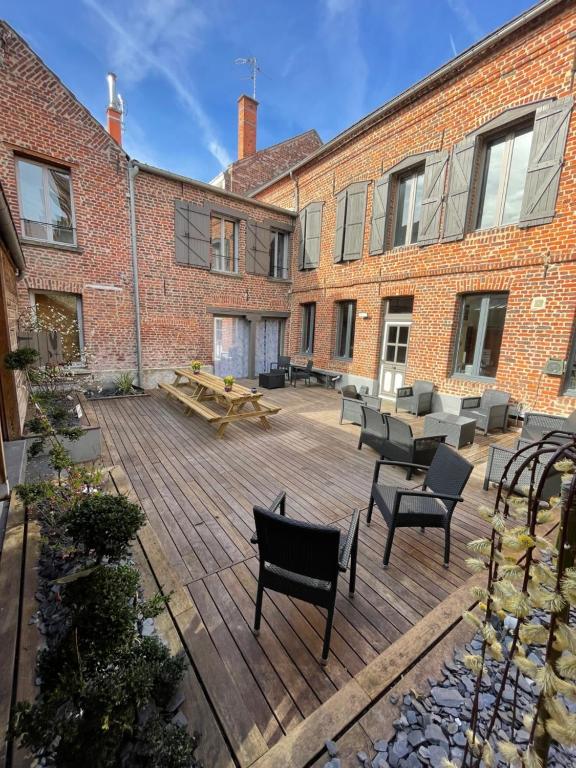 a patio with chairs and tables in front of a brick building at Douai house in Douai
