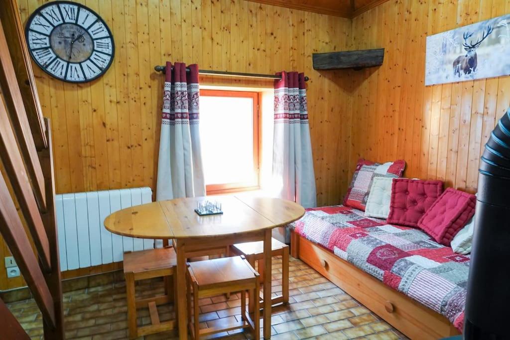 um quarto com uma mesa e uma cama e um relógio em Les 3 marmottes duplex proche de la station Les Karellis em Montricher-Albanne