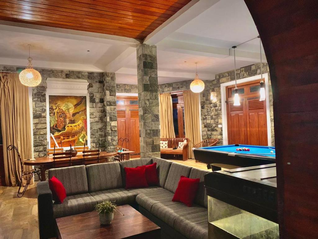 a living room with a couch and a pool table at Diyon Bungalow in Bandarawela