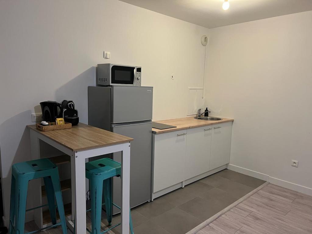 uma cozinha com um frigorífico, uma mesa e bancos em Appartement idéalement placé em Villeparisis