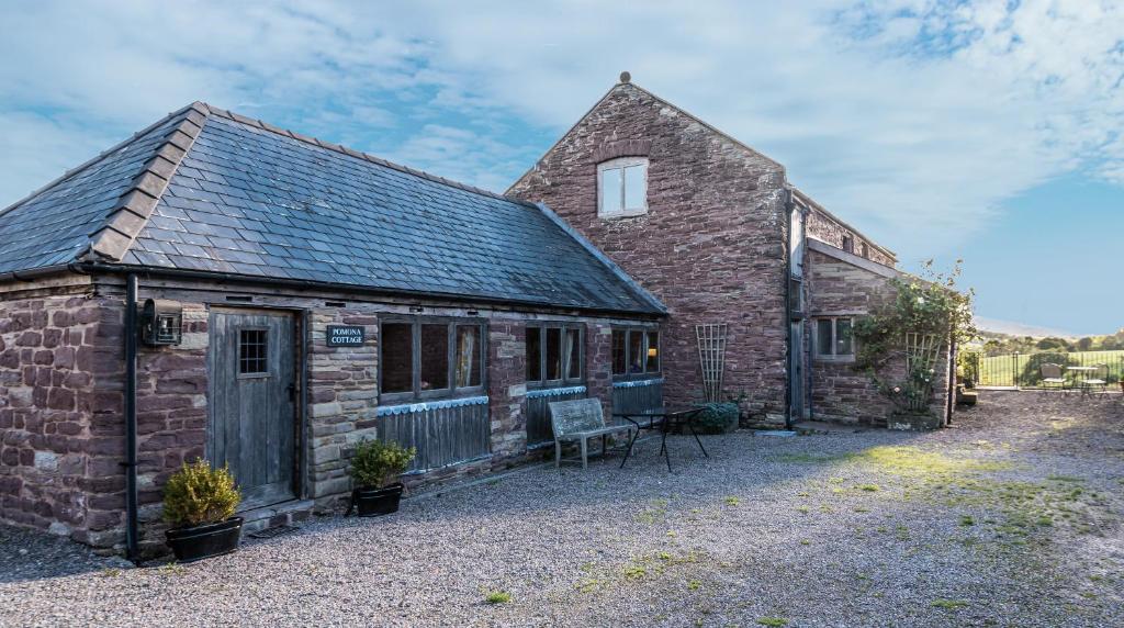 an old brick building with a bench in front of it at Pomona Cottage at Old King Street Llama Farm in Ewyas Harold