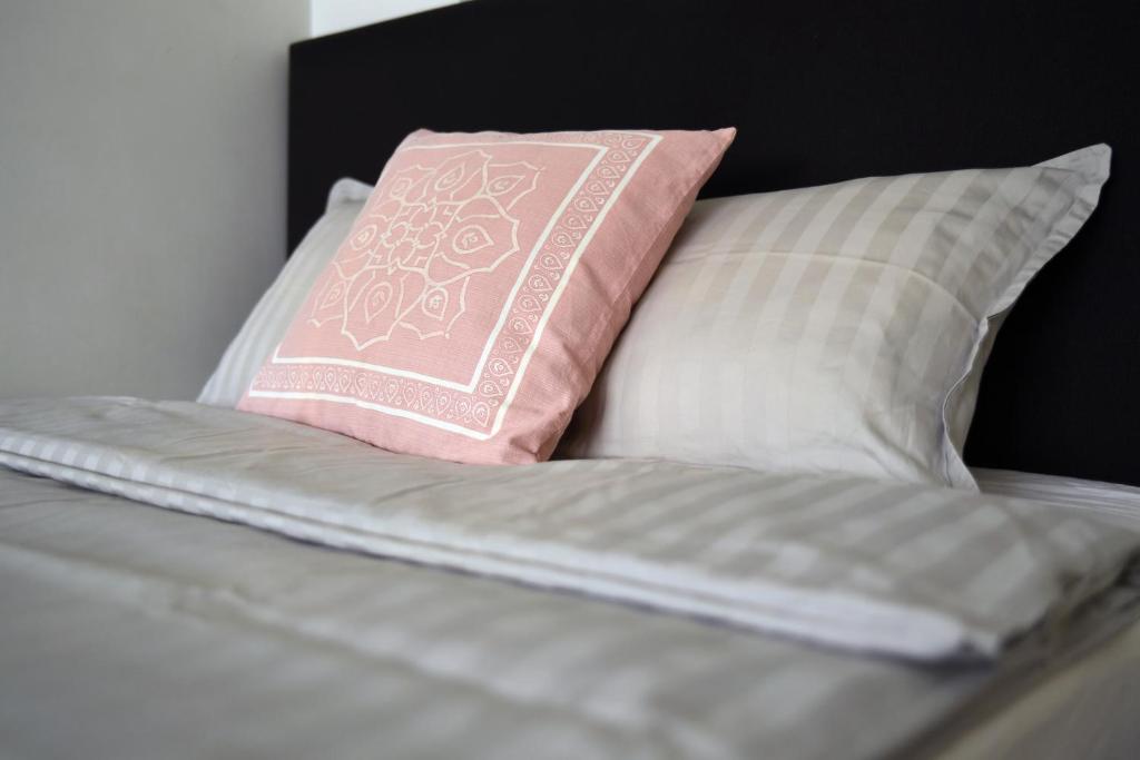 a bed with a pink pillow and some pillows at Scandinavian Home 17 city Center Työmiehenkatu 2B in Helsinki