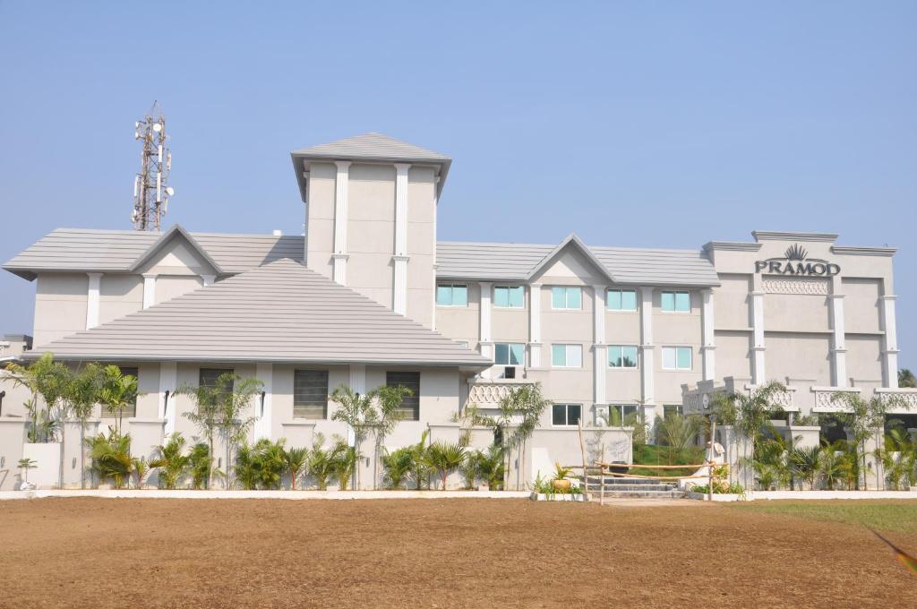 a large white building with palm trees in front of it at Pramod Convention & Beach Resorts in Puri