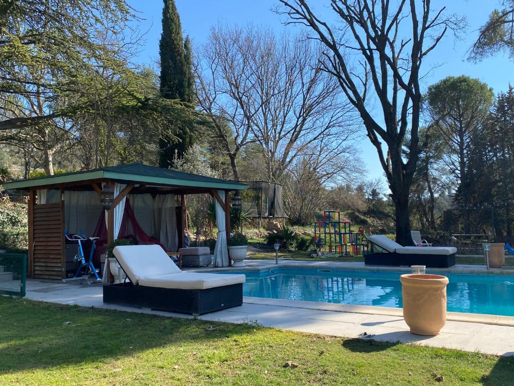 uma piscina com um gazebo e duas cadeiras ao lado em Maison + piscine à 10 min d'Aix en Pce em Meyreuil