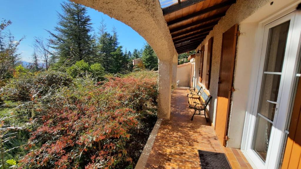 a porch with a bench on the side of a house at VILLA LA LURETTE, appartement et studio in Saint-Étienne-les-Orgues