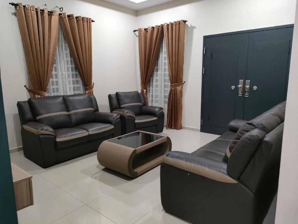 a living room with couches and chairs and a door at D'Kampung Homestay Melaka in Melaka