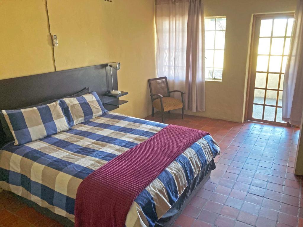 a bedroom with a bed with a blue and white blanket at Kalahari Homestead in Khemsbok