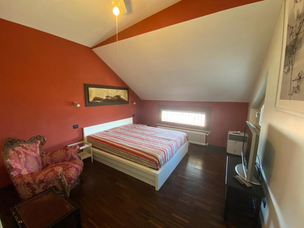 a bedroom with red walls and a bed and a chair at Casa Morena near Anagnina metro in Rome
