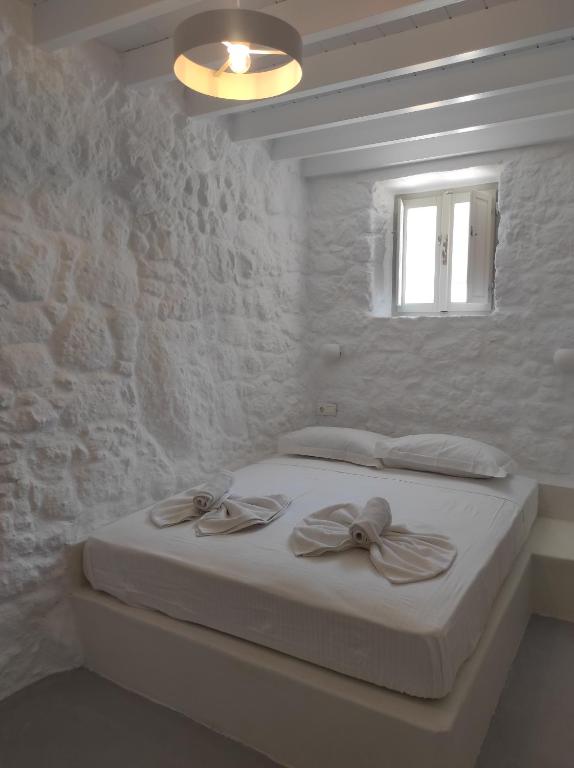 a white bedroom with a bed with a window at Oniropagida Nisyros apartment #1 in Nikiá