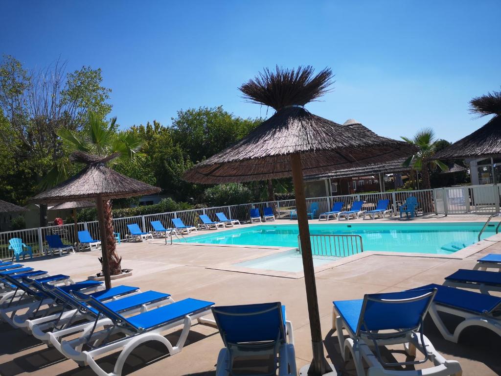 una piscina con sillas y sombrillas azules en Camping Le Fou du Roi, en Lansargues