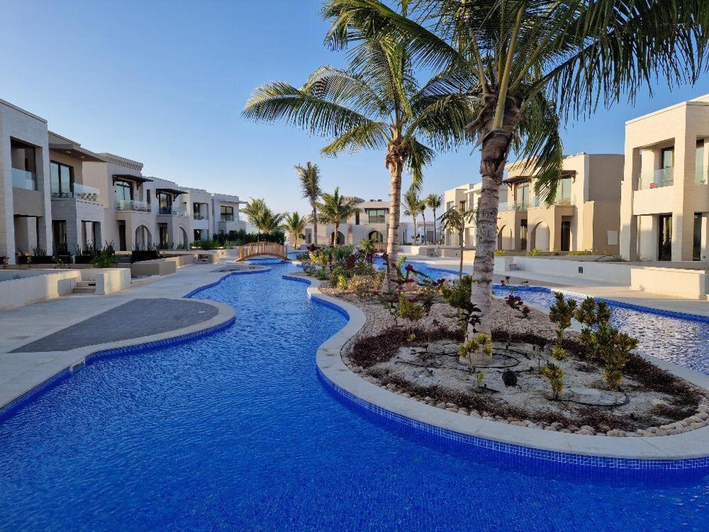 um resort com água azul, palmeiras e edifícios em Glory Salalah Miko 1 em Salalah