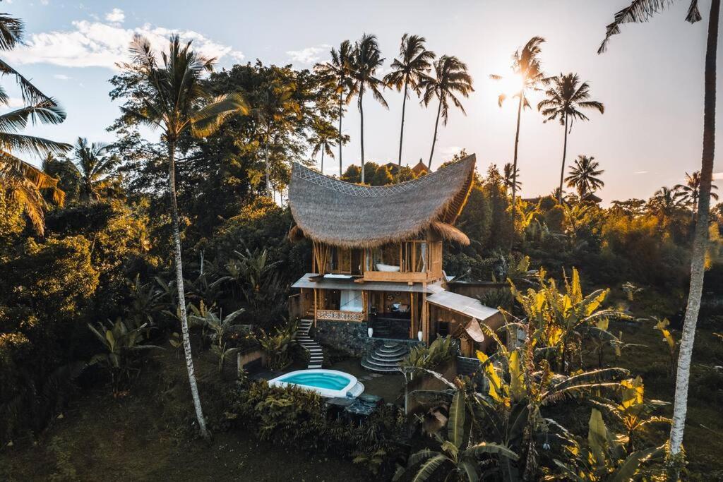 a house in the middle of a forest with palm trees at Makerti Bali~Bamboo House in Selat