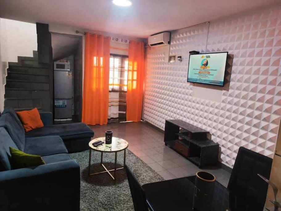a living room with a couch and a tv at Bel Appartement meublé à Bastos in Yaoundé