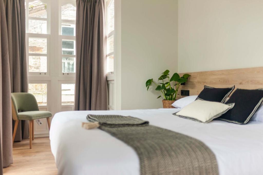 a bedroom with a white bed with a chair and a window at Albatros in Puentedeume