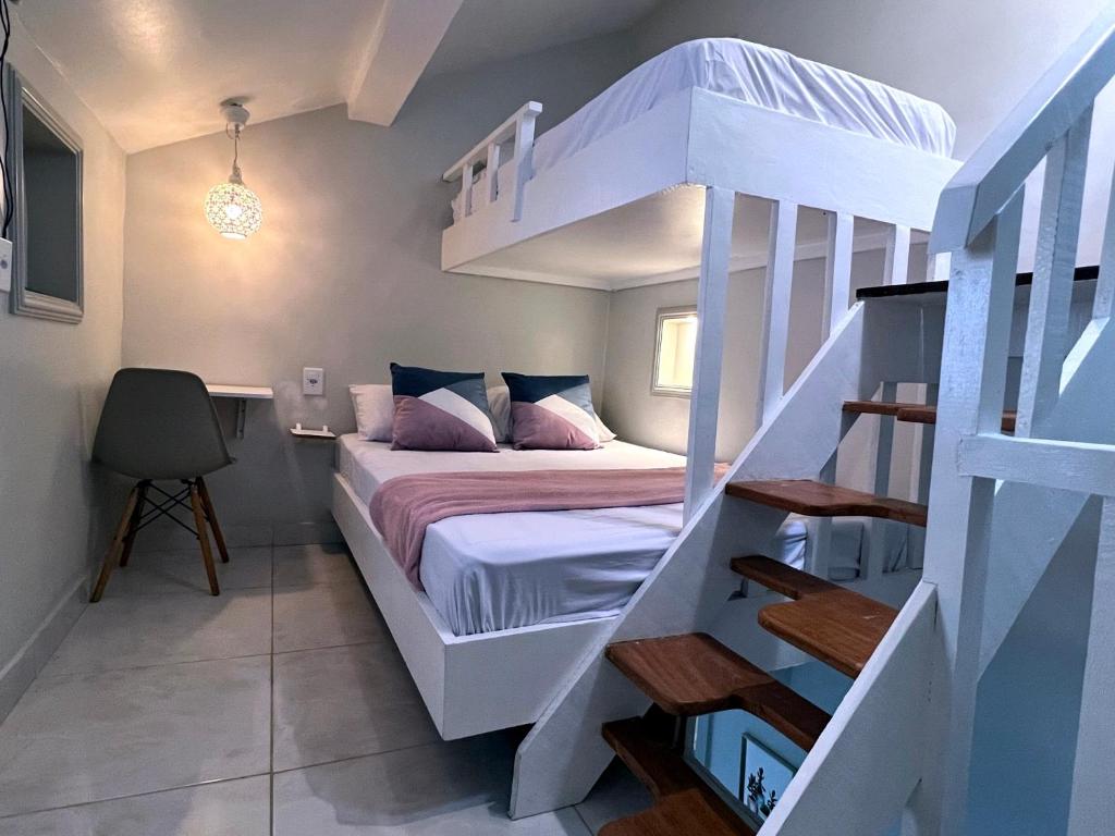 a bedroom with a white bunk bed and a staircase at Studio Apartamento Lindo na Rua das Pedras in Búzios
