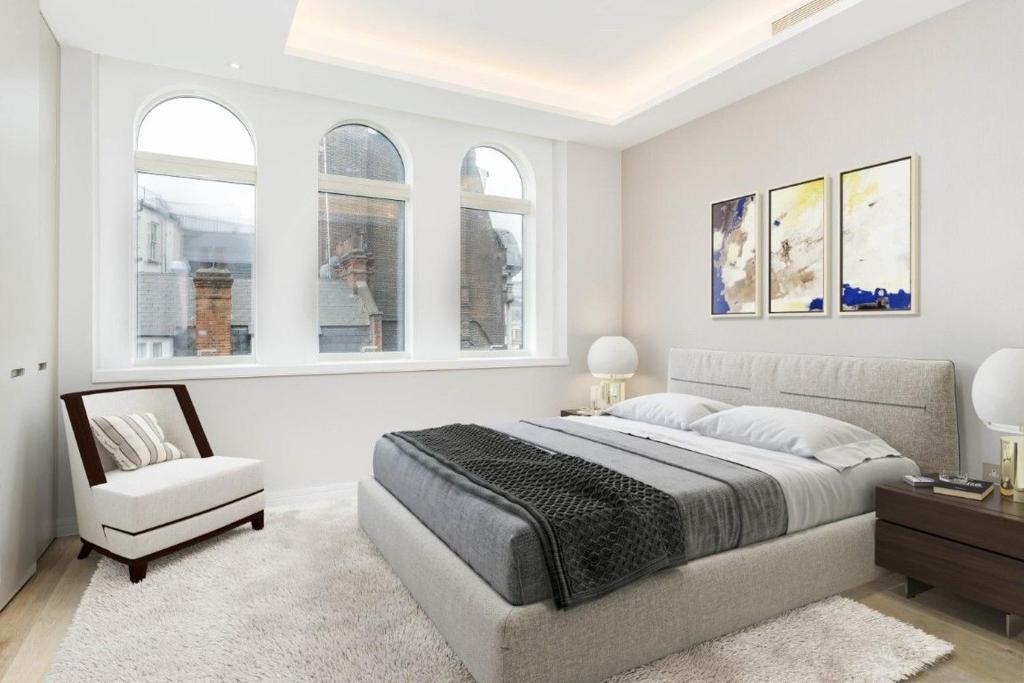 sypialnia z łóżkiem, krzesłem i oknami w obiekcie Covent Garden Luxury Apartment w Londynie