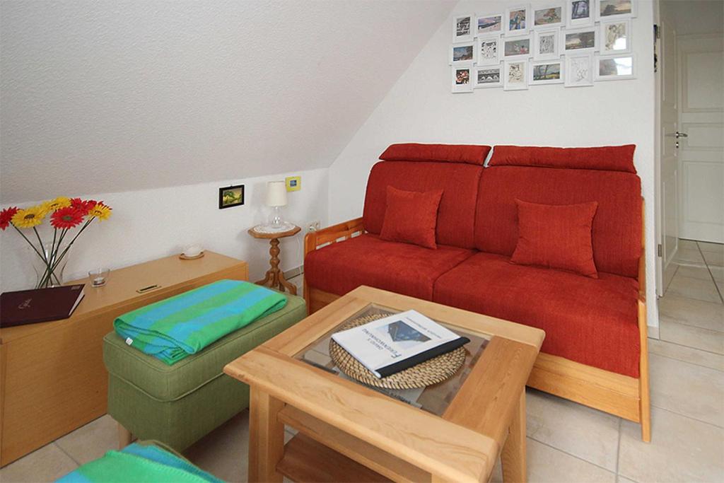 een woonkamer met een rode bank en een tafel bij Davids Ferienwohnung in Wustrow