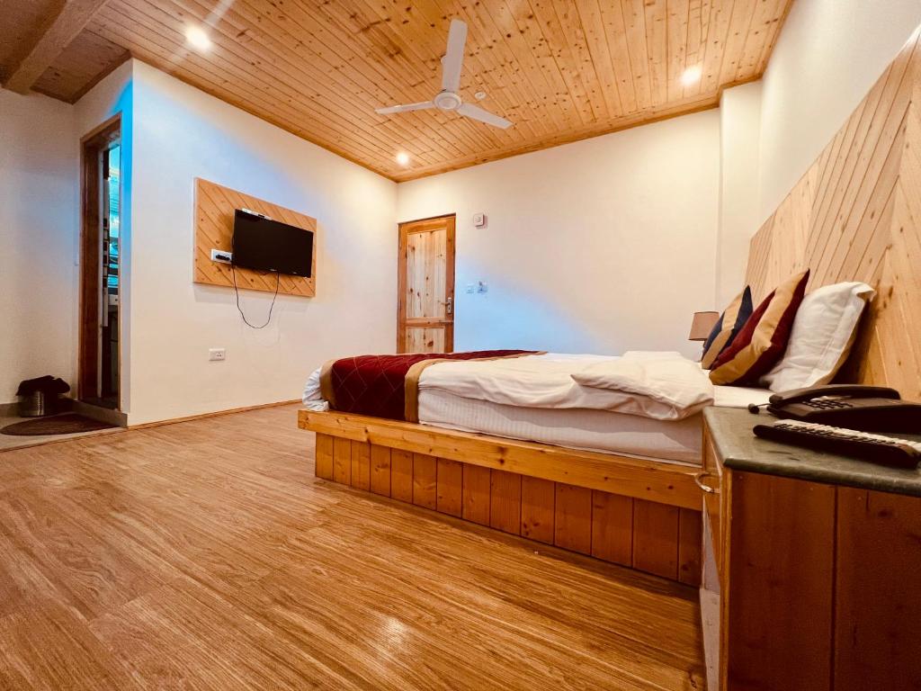 um quarto com uma cama e uma televisão na parede em Royal View Inn em Manali