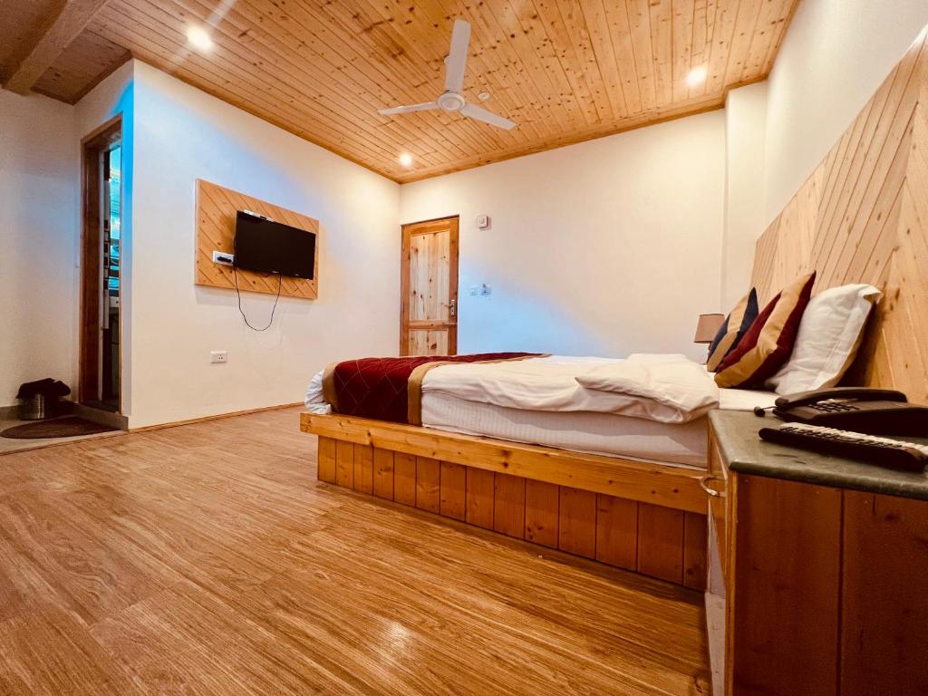 a bedroom with a bed and a tv on a wall at Royal View Inn in Manāli