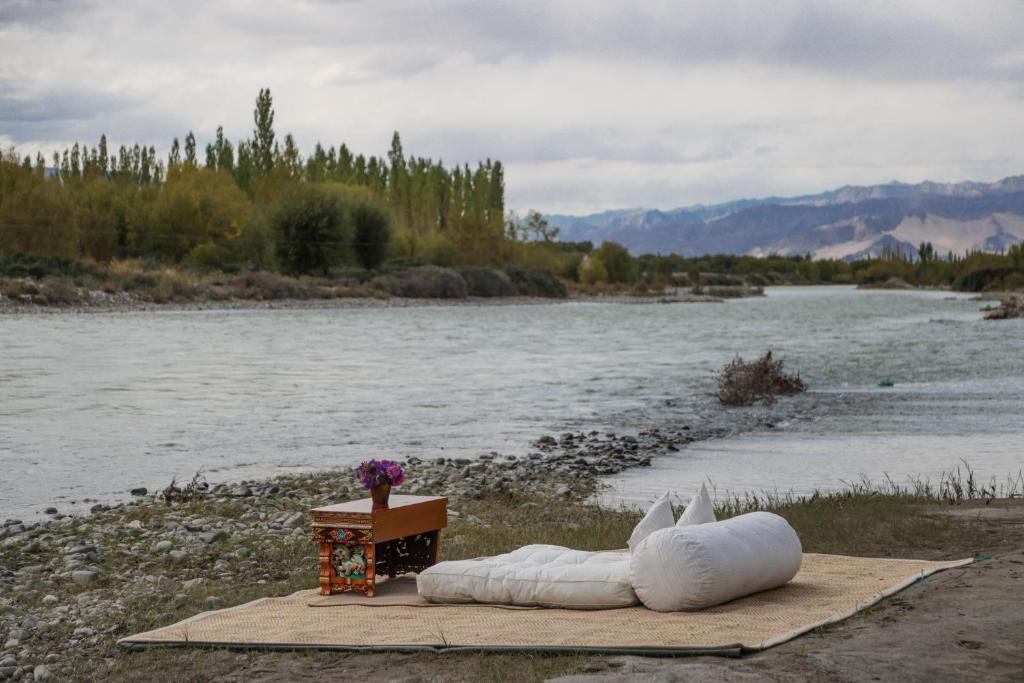 a couple of white pillows on a table next to a river at Chamba Camp Diskit by TUTC in Nubra