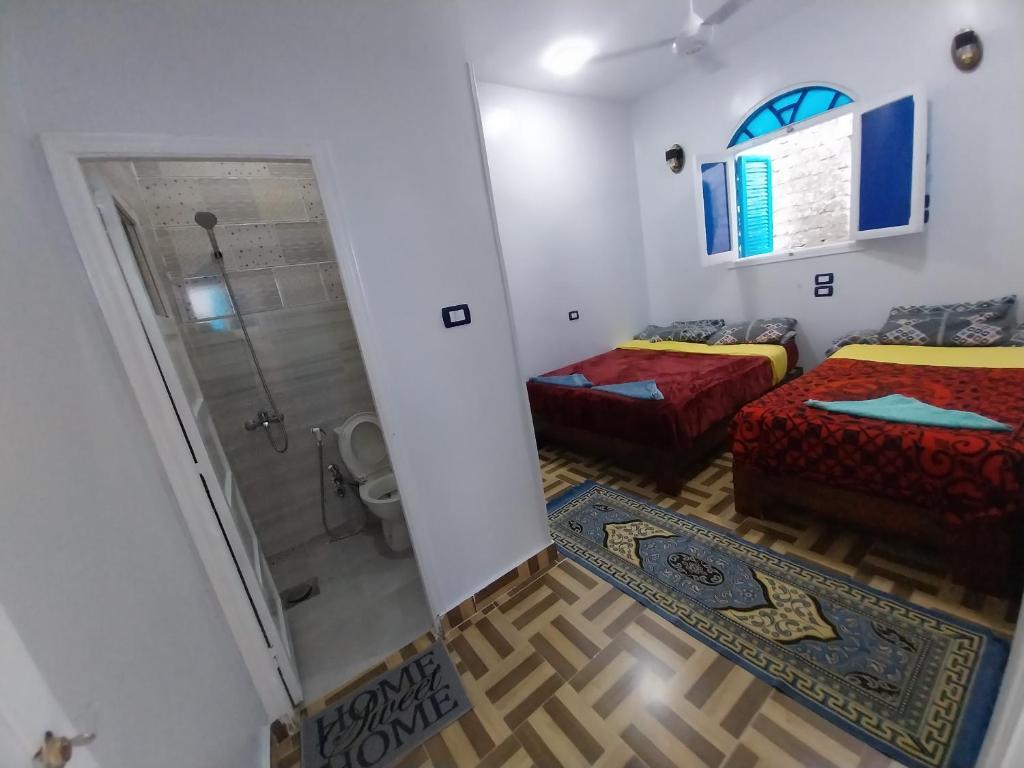 a small room with two beds and a shower at Kayan Guest House in Aswan