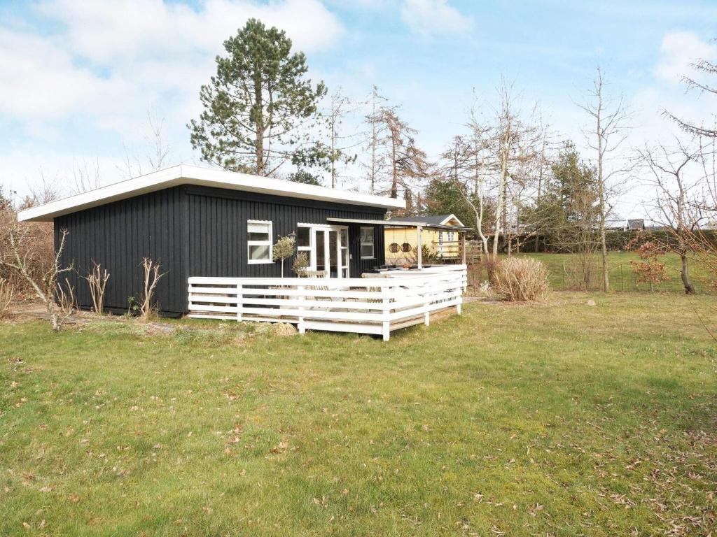 霍爾拜克的住宿－Holiday home Holbæk III，田野上带白色围栏的黑色房子