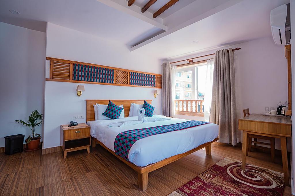 1 dormitorio con 1 cama, escritorio y ventana en Himalayan Glory Inn, en Pokhara