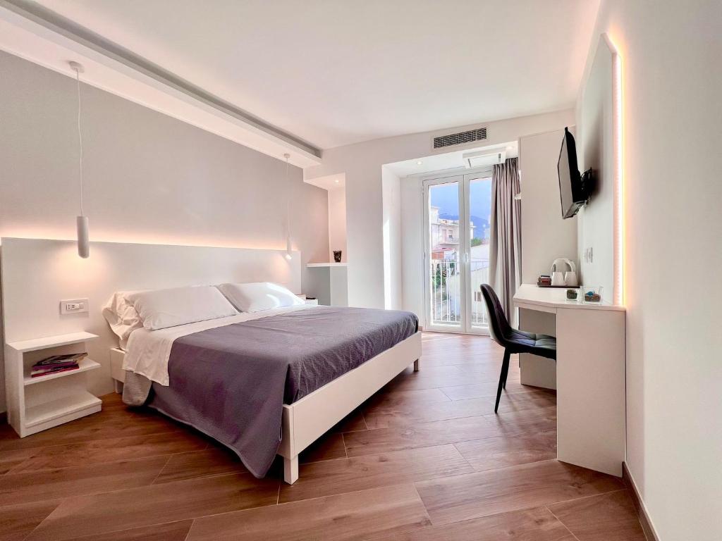 a white bedroom with a bed and a chair at Tropea Il Tridente Accommodations in Tropea