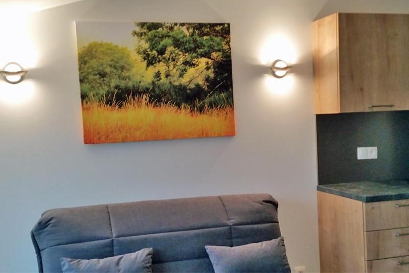 a living room with a couch and a painting on the wall at VILLA LA LURETTE, appartement et studio in Saint-Étienne-les-Orgues