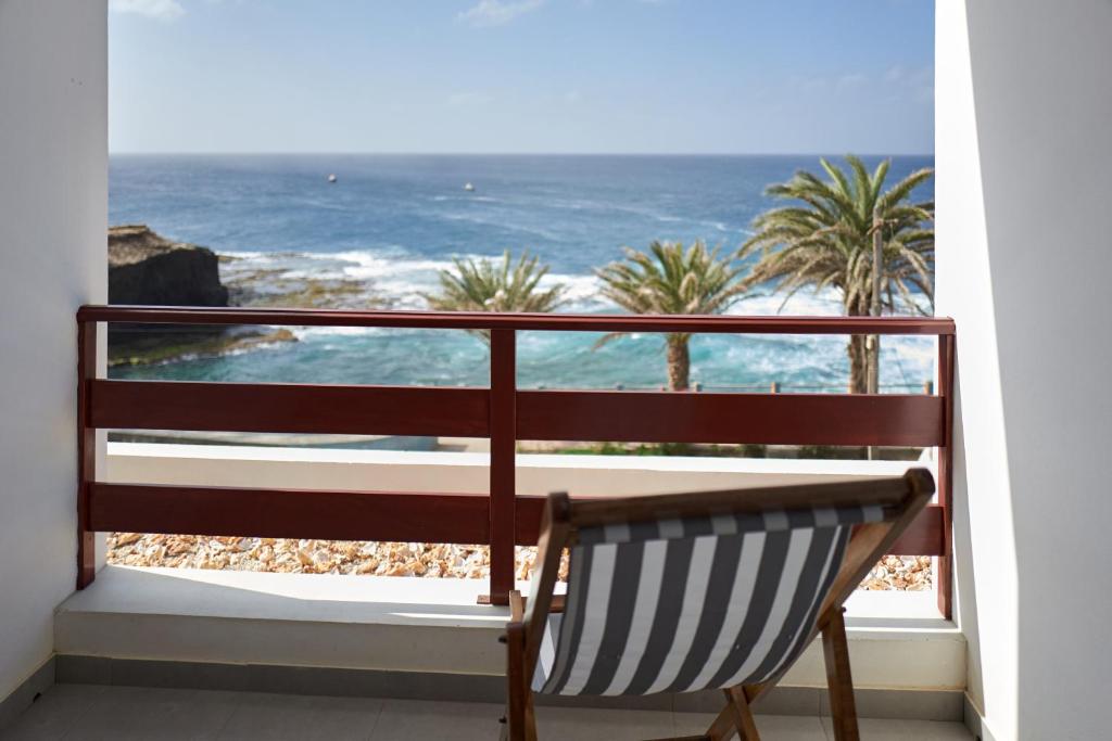 un banco sentado en un balcón con vistas al océano en Música do Mar, en Ponta do Sol