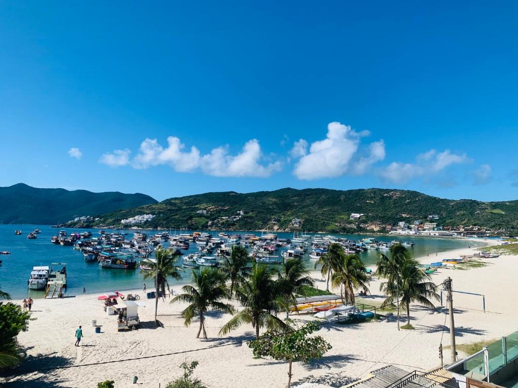 a beach with a bunch of boats in the water at Flat dos Anjos in Arraial do Cabo
