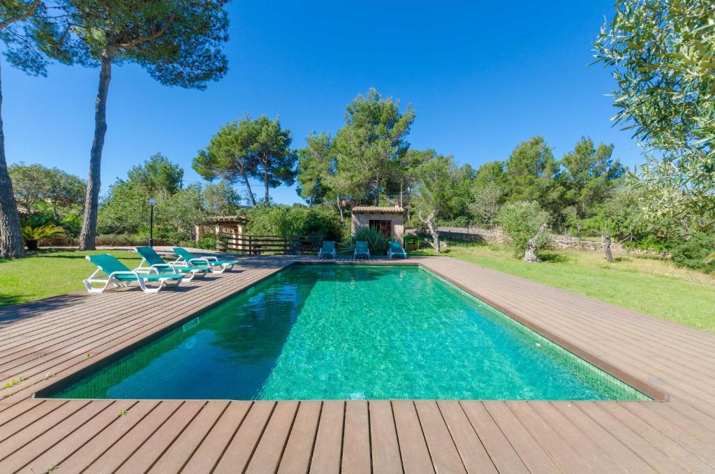 una piscina con sillas y una terraza de madera en YourHouse Son Jaumell, en Capdepera
