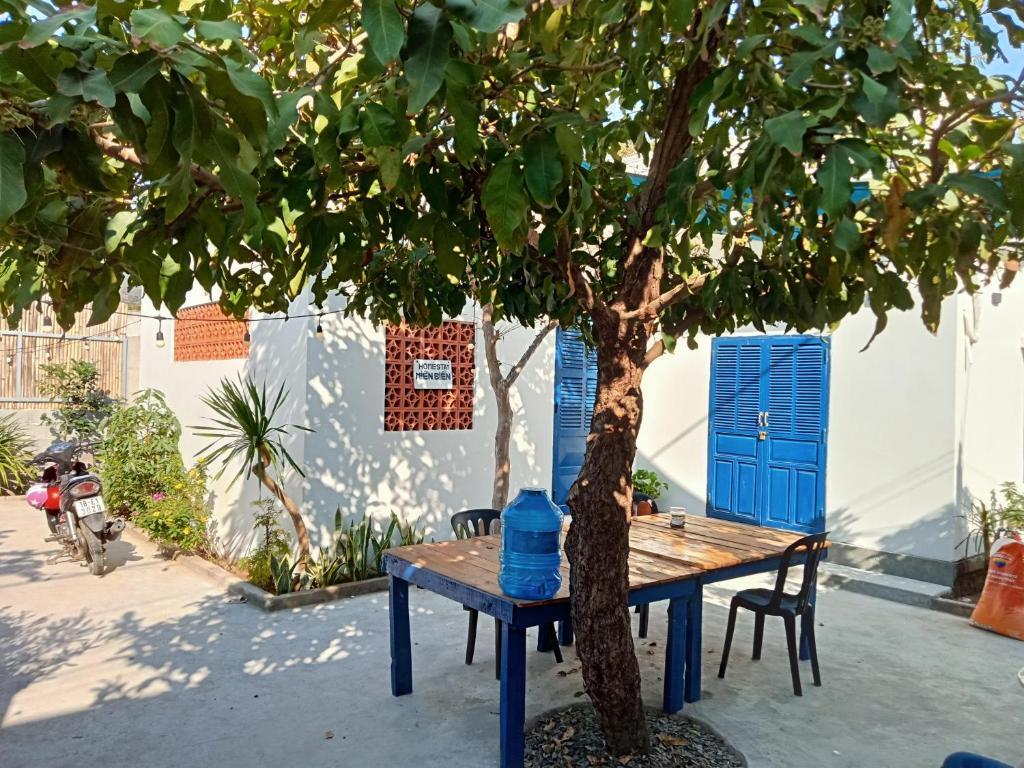 uma mesa azul ao lado de uma árvore com uma garrafa azul em Homestay Miền Biển Vĩnh Hy 2 em Vinh Hy
