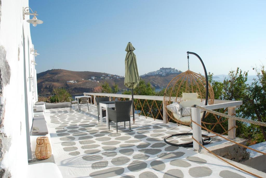 un patio con mesa, sillas y sombrilla en Siesta Villas nearby Tzanaki Beach Livadi en Livadi Astypalaias