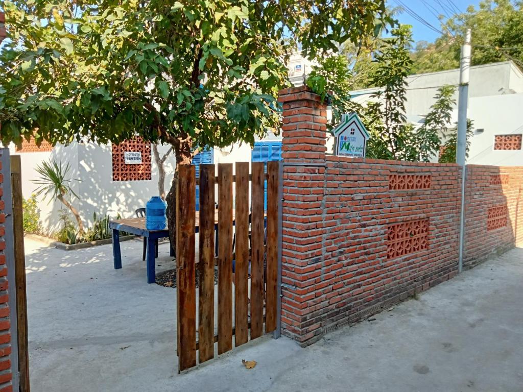a brick fence with a wooden gate and a tree at Homestay Miền Biển Vĩnh Hy in Vĩnh Hy