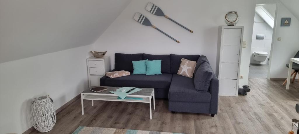 ein Wohnzimmer mit einem blauen Sofa und einem Tisch in der Unterkunft Haus am Meer in Schweiburg