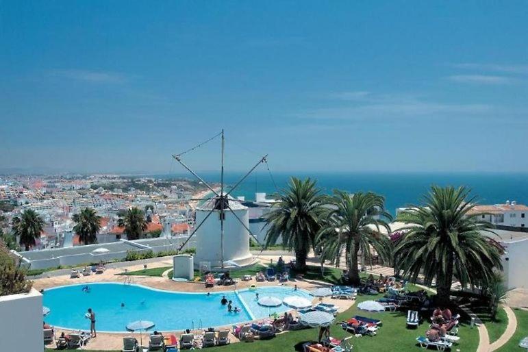 ein großer Pool mit einer Windmühle im Hintergrund in der Unterkunft douceur d'algarve in Albufeira