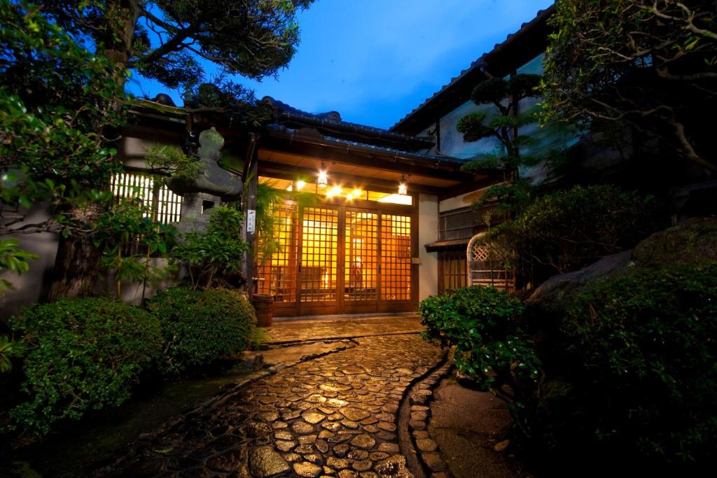 a japanese house with a gate at night at Ryokan Sennari (13 years or older) in Beppu