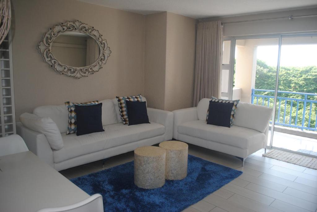 a living room with two white couches and a mirror at 65 Key Largo in Kingsburgh