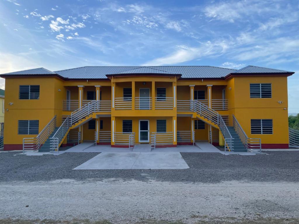 a yellow house with stairs in front of it at Poinciana Apartments - Holiday Rental in Woods