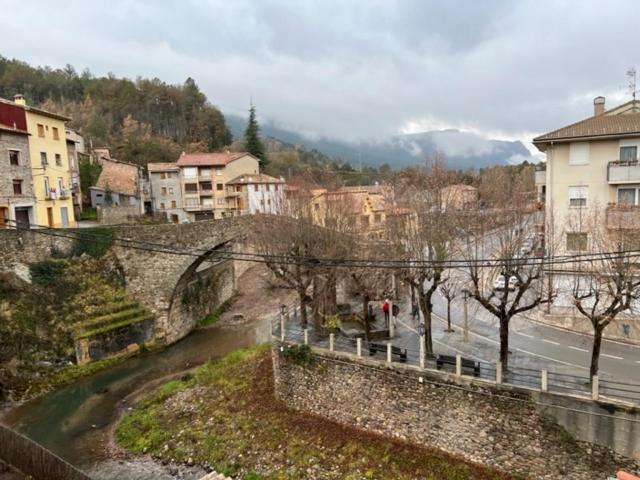 een brug over een rivier in een stad met gebouwen bij Hostal Cal Pericas in La Pobla de Lillet