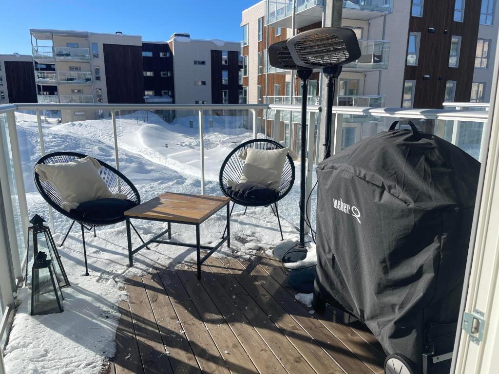2 Stühle und ein Tisch auf einem Balkon mit Schnee in der Unterkunft Leilighet sentralt i Tromsø in Tromsø
