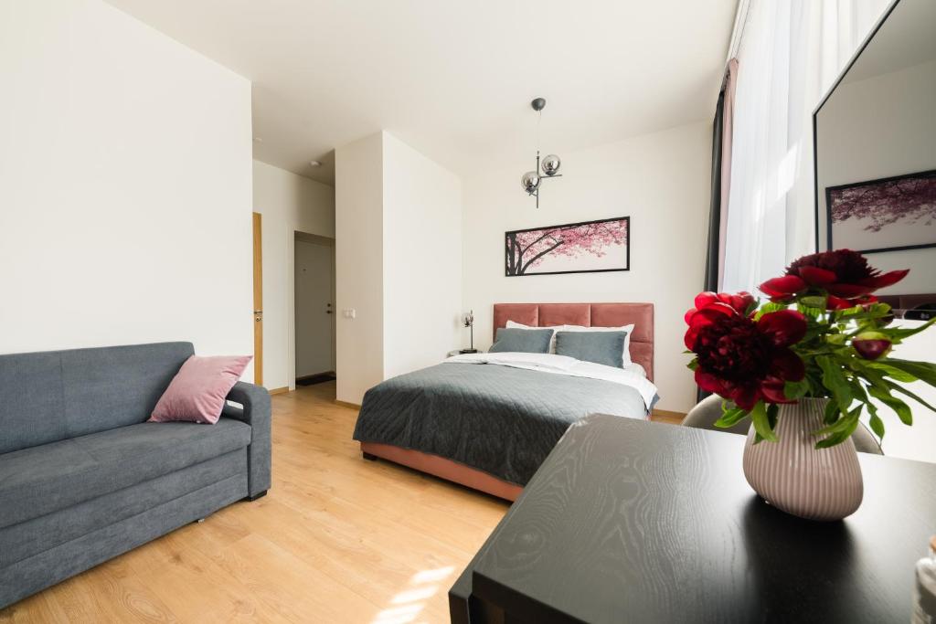 a bedroom with a bed and a vase of red roses at West In Apartment in Liepāja