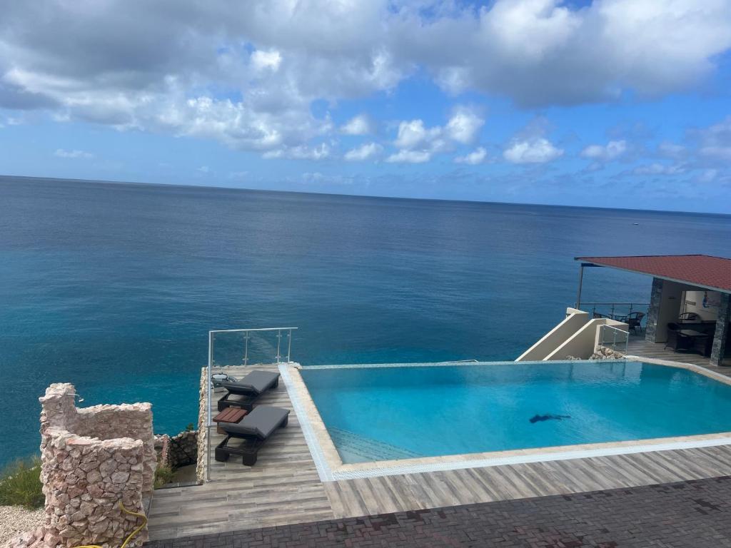 a swimming pool with the ocean in the background at Lagun Sunset Resort All Natural Clothing Optional in Lagun