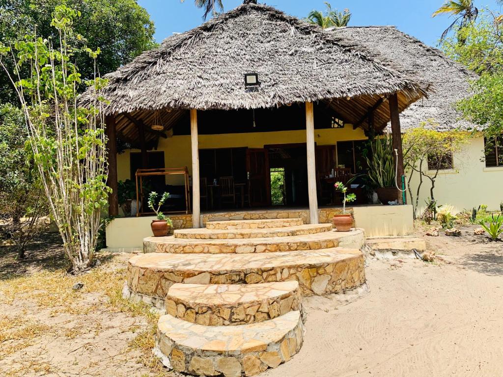 a group of steps leading to a building with a thatch roof at Ushongo Beach Cottages - Family House in Tanga